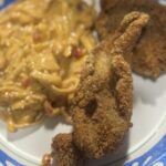 A plate of fried catfish served with crawfish fettuccine