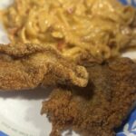Cornmeal crusted fried catfish served alongside crawfish fettuccine