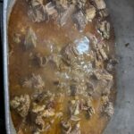 A large pot of oxtails simmering in seasoned gravy